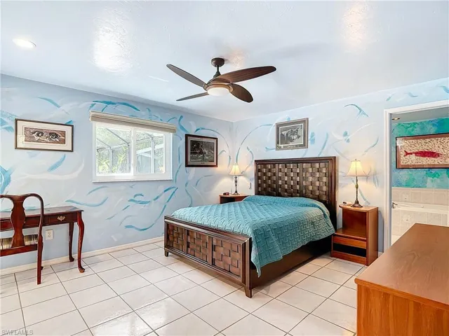 Bedroom with tile patterned floors, ensuite bath, and ceiling fan