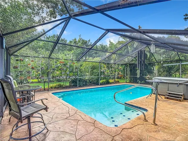 View of swimming pool with a patio area, a hot tub, and glass enclosure