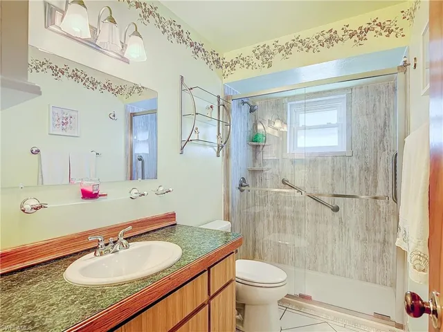 Bathroom with tile patterned flooring, toilet, vanity, and an enclosed shower
