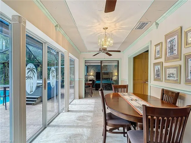 Dining area with light tile patterned flooring and ceiling fan with notable chandelier