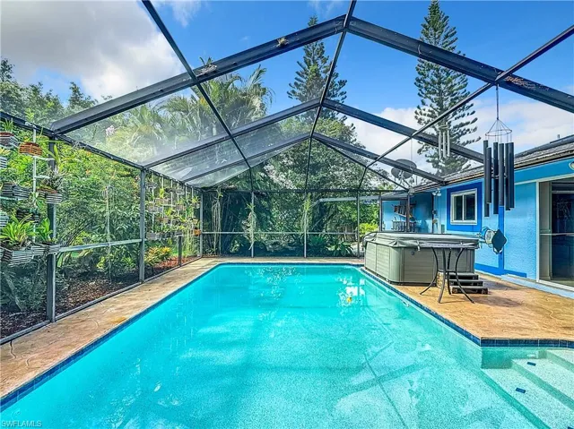 View of pool featuring a lanai and a hot tub