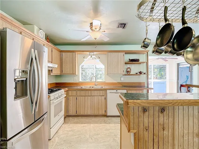 Kitchen featuring light tile patterned floors, white appliances, sink, and plenty of natural light