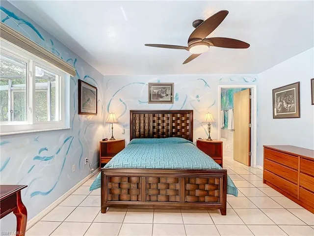 Bedroom featuring connected bathroom, light tile patterned floors, and ceiling fan