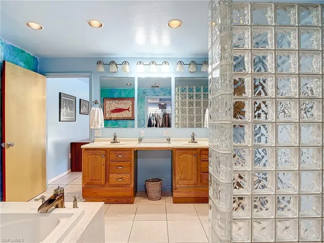Bathroom featuring tiled bath, dual vanity, and tile patterned floors