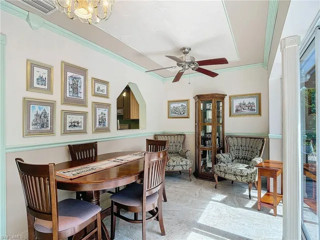 Tiled dining area with ceiling fan with notable chandelier and crown molding
