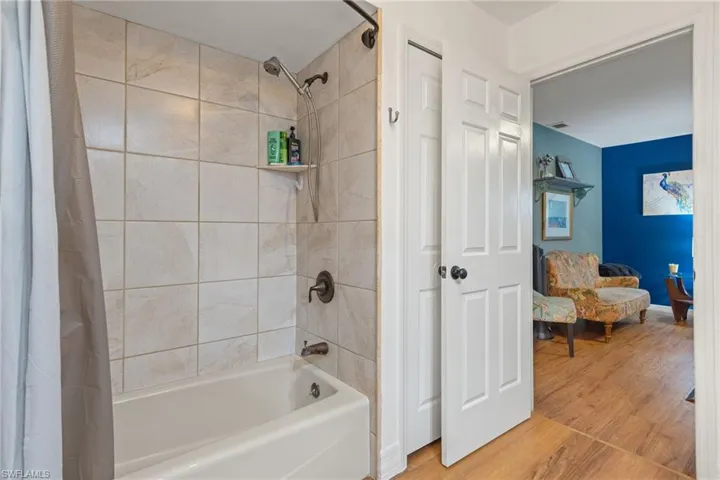 Bathroom with shower / bath combination with curtain and hardwood / wood-style floors