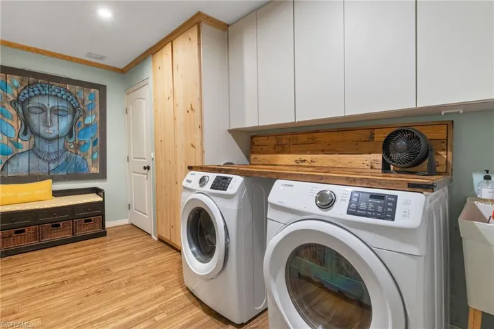 Laundry area featuring washer and dryer, light hardwood / wood-style floors, sink, and cabinets