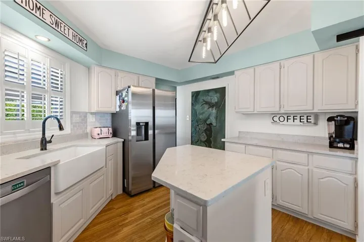 Kitchen with a center island, white cabinetry, light hardwood / wood-style flooring, and stainless steel appliances