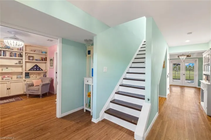 Staircase with built in features, light hardwood / wood-style flooring, and french doors