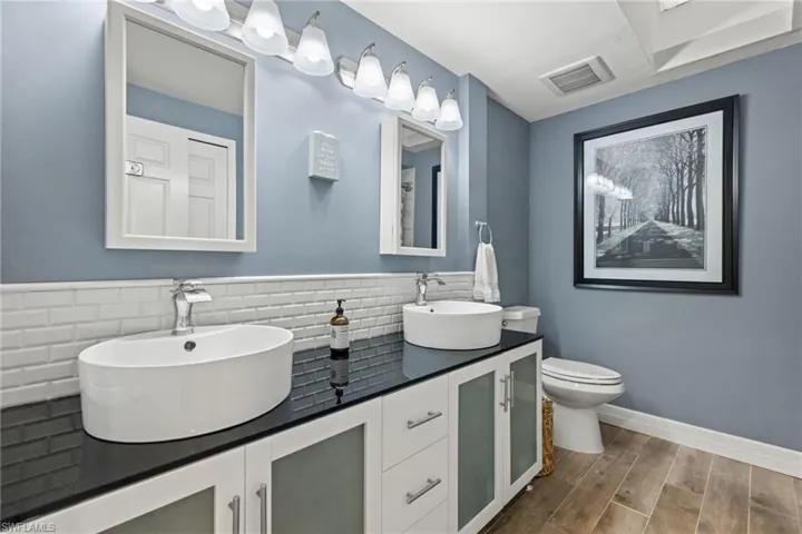 Bathroom featuring backsplash, double vanity, toilet, and hardwood / wood-style flooring