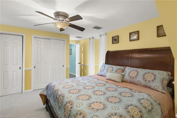 Carpeted bedroom with two closets and ceiling fan
