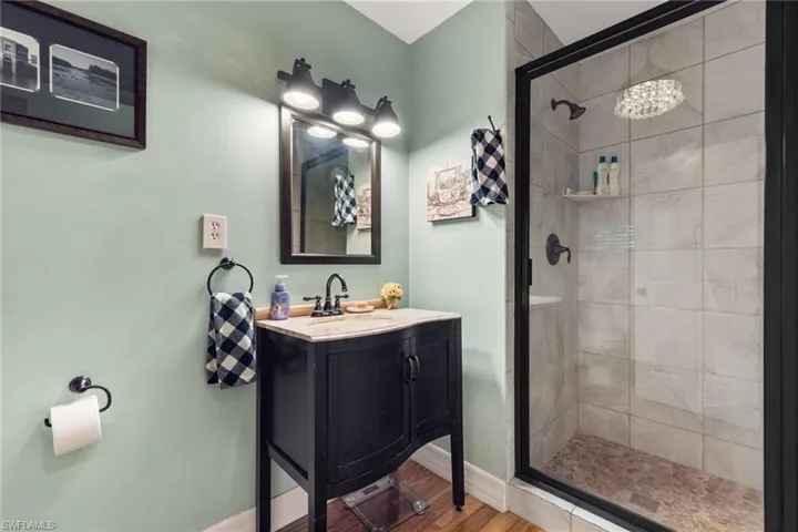 Bathroom featuring a shower with shower door, hardwood / wood-style flooring, and large vanity