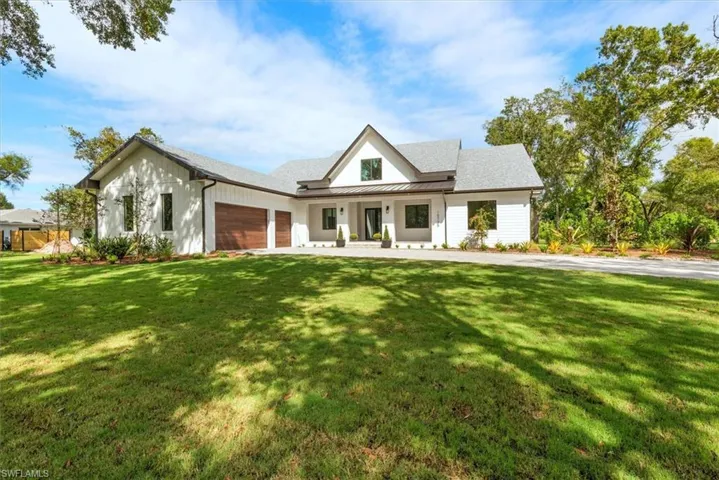 Modern farmhouse with a standing seam roof, covered porch, a front yard, and a metal roof
