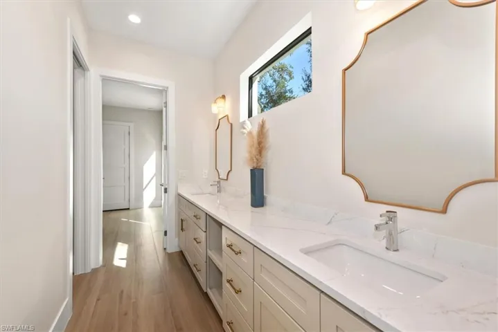 Full bathroom with double vanity, light wood finished floors, and recessed lighting