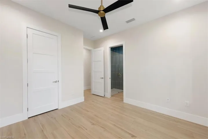 Unfurnished bedroom featuring light wood-style flooring, ceiling fan, recessed lighting, and ensuite bathroom