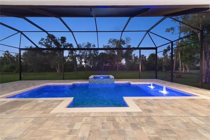 View of pool featuring a lanai, a pool with connected hot tub, a sunroom, a lawn, and a patio area