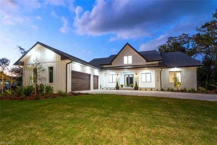 Modern farmhouse with covered porch, a lawn, a garage, a shingled roof, and driveway