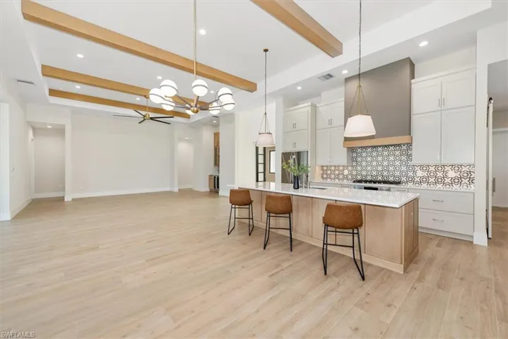 Kitchen with backsplash, beamed ceiling, decorative light fixtures, a spacious island, and open floor plan
