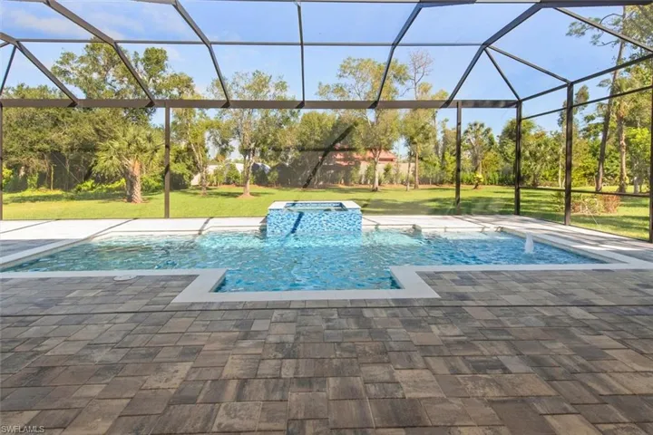 View of pool featuring a lawn, a lanai, a sunroom, and a pool with connected hot tub