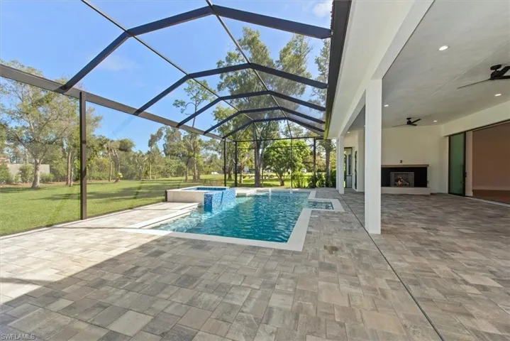 View of swimming pool featuring a ceiling fan, a sunroom, a patio area, a yard, and a pool with connected hot tub