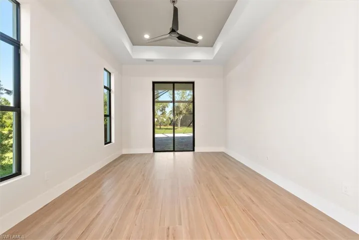 Spare room featuring a raised ceiling, light wood-style flooring, recessed lighting, and a ceiling fan
