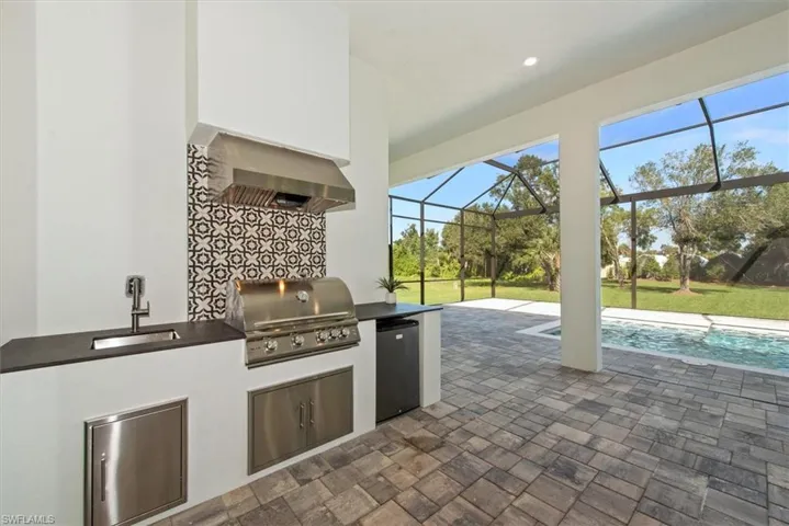 View of patio featuring an outdoor pool, a sunroom, a lanai, and exterior kitchen