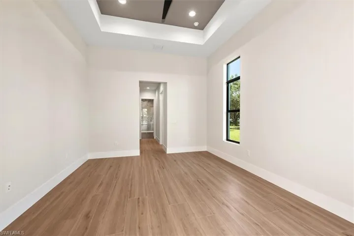 Unfurnished room with recessed lighting, light wood-type flooring, and a tray ceiling