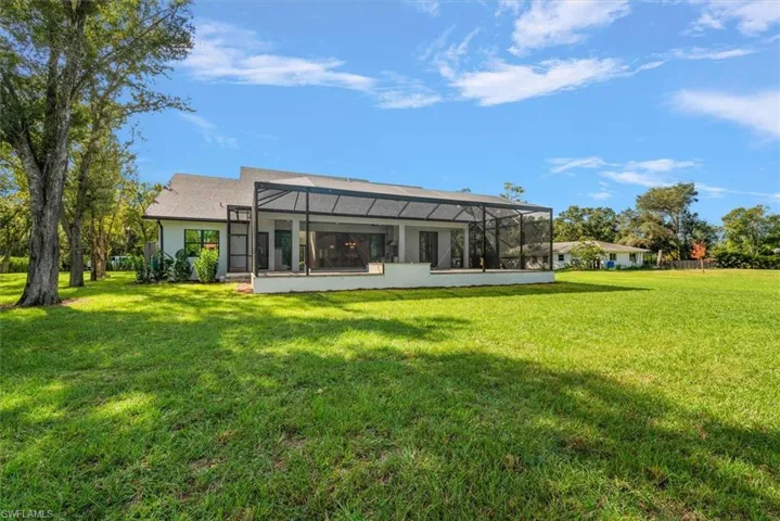 Back of house featuring a yard, a sunroom, a lanai, and stucco siding