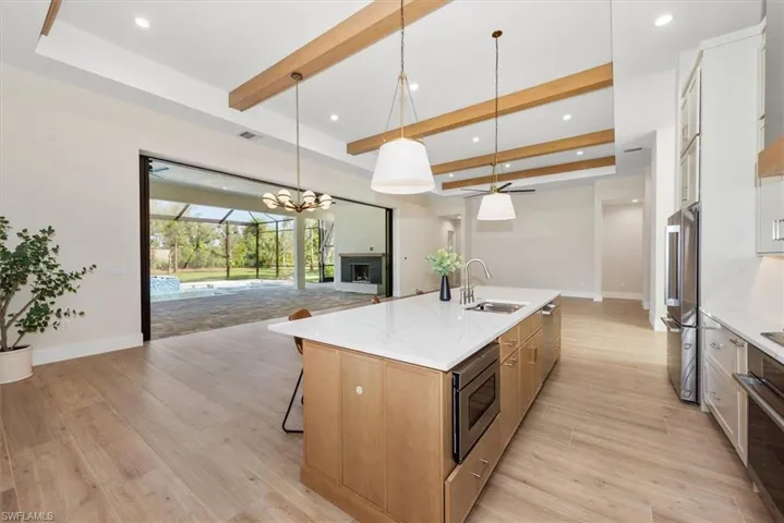 Kitchen featuring beam ceiling, open floor plan, decorative light fixtures, a breakfast bar, and a chandelier