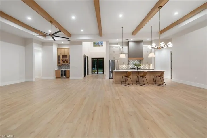 Kitchen with open floor plan, backsplash, decorative light fixtures, a breakfast bar area, and a large island with sink