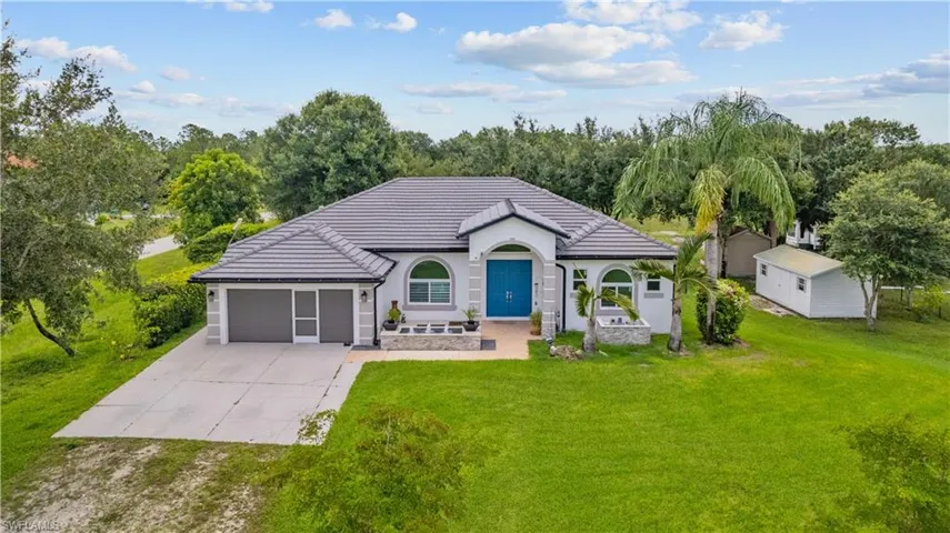Contemporary stucco exterior with a tile roof, an arched entry featuring a double blue door, and a two-car garage with screened doors
