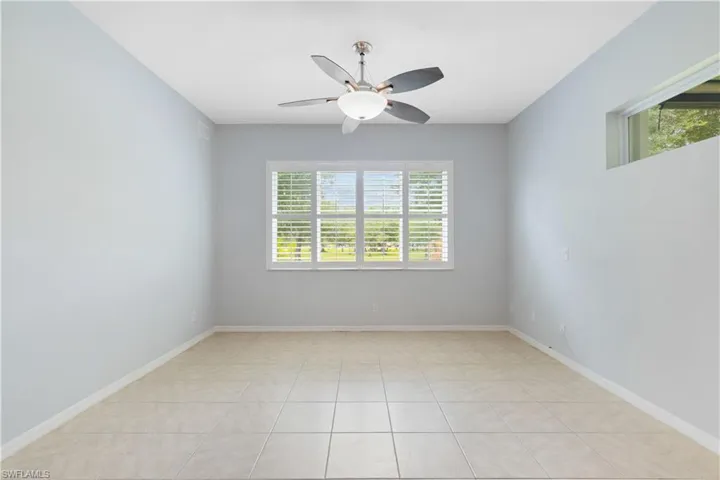 Spacious room featuring tile flooring, a ceiling fan with integrated lighting, and a large window with white blinds