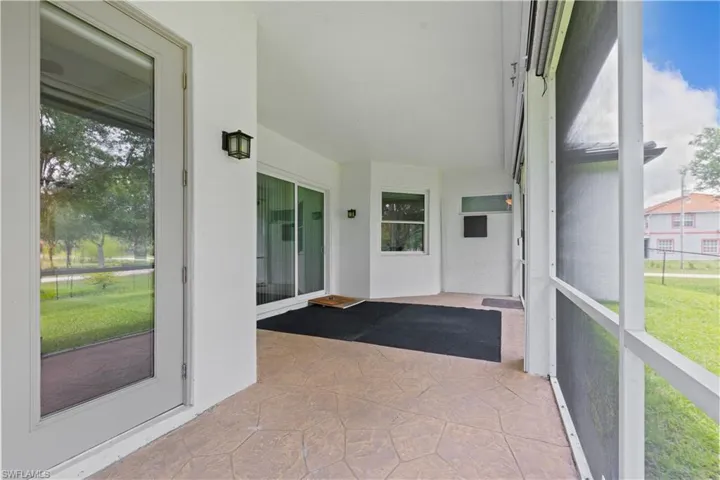 Expansive covered patio featuring stamped concrete flooring, white stucco walls, and a screened enclosure