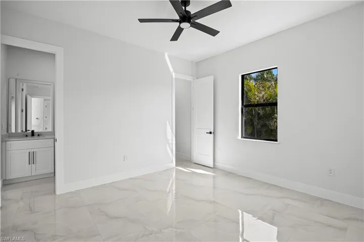 Unfurnished bedroom featuring sink, ensuite bath, and ceiling fan