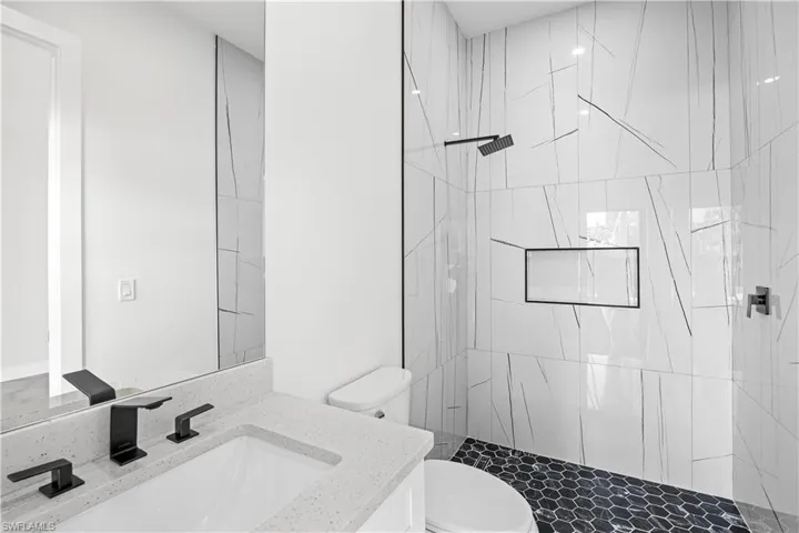 Bathroom with a tile shower, vanity, and toilet