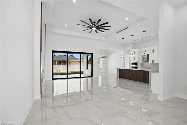Unfurnished living room featuring a tray ceiling and ceiling fan