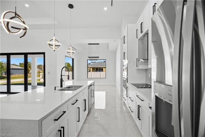 Kitchen featuring white cabinetry, decorative light fixtures, a kitchen island with sink, and stainless steel fridge with ice dispenser