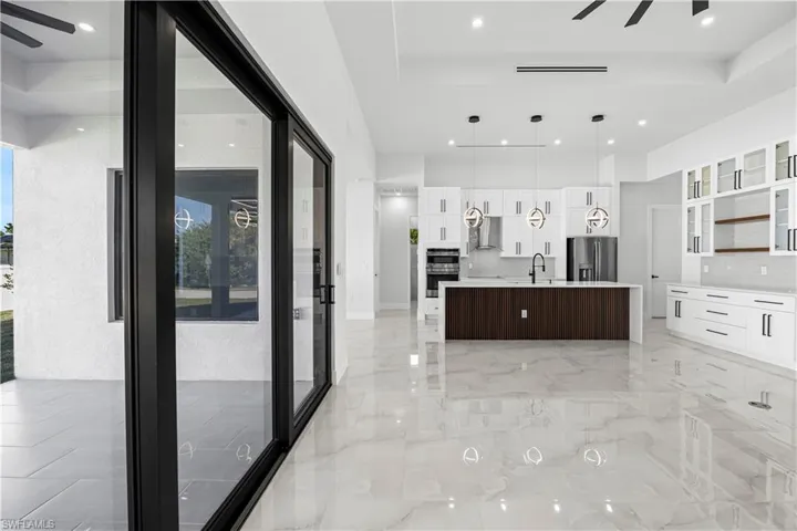 Kitchen with white cabinetry, ceiling fan, appliances with stainless steel finishes, and an island with sink