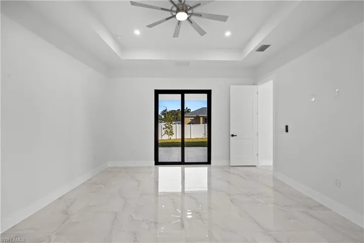Empty room featuring ceiling fan and a tray ceiling