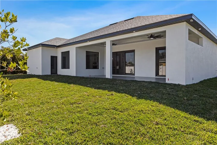 Rear view of house with ceiling fan and a lawn