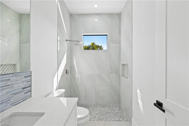 Bathroom with vanity, a tile shower, and toilet