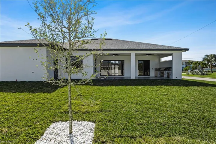 Rear view of house with a yard, ceiling fan, and an outdoor kitchen