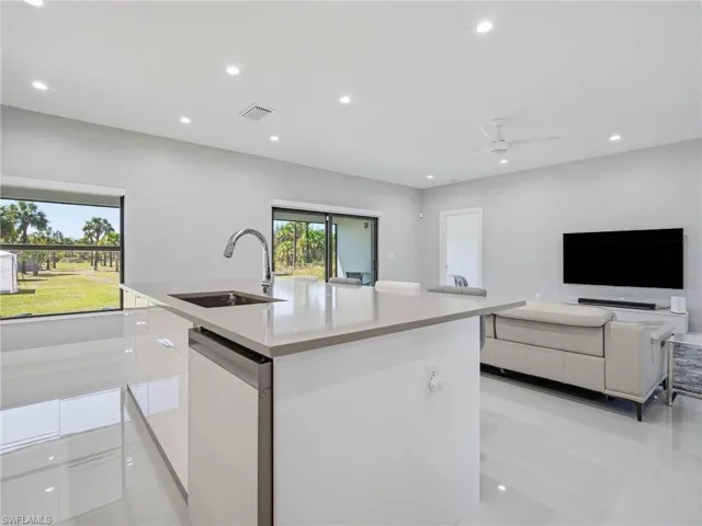 Kitchen with white cabinets, modern cabinets, dishwasher, light stone countertops, and open floor plan