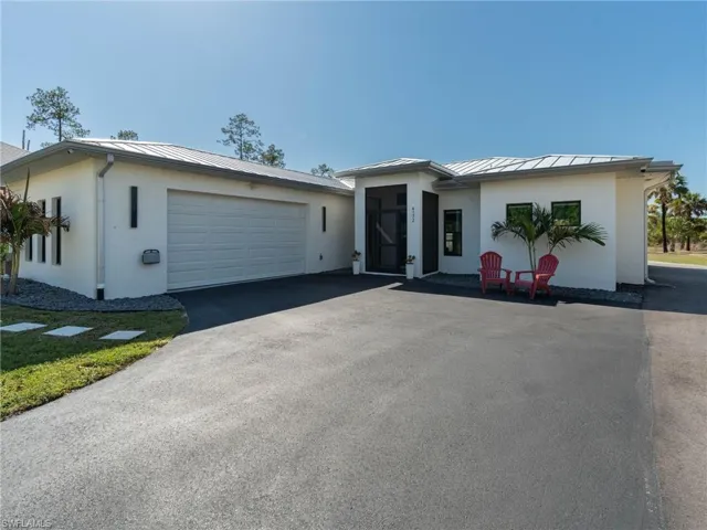 View of front of property with a standing seam roof, stucco siding, driveway, and an attached garage