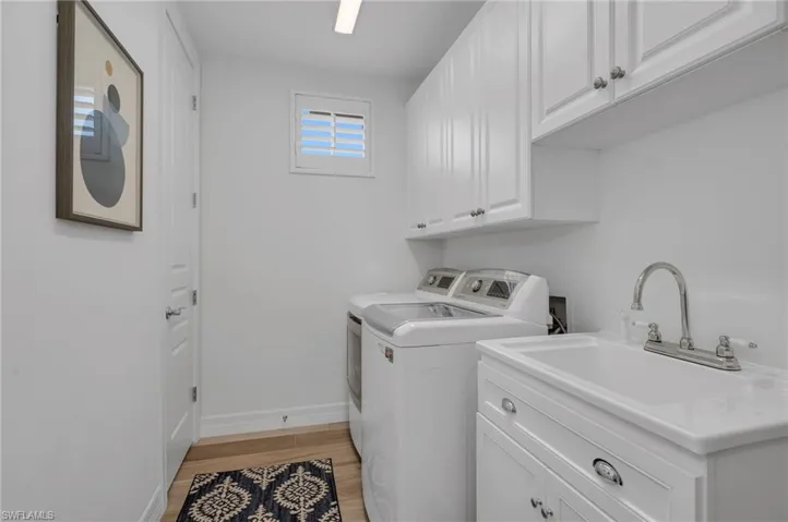 Laundry room wit abundant storage and a deep sink, with a 50-gallon water heater in the closet to the left.