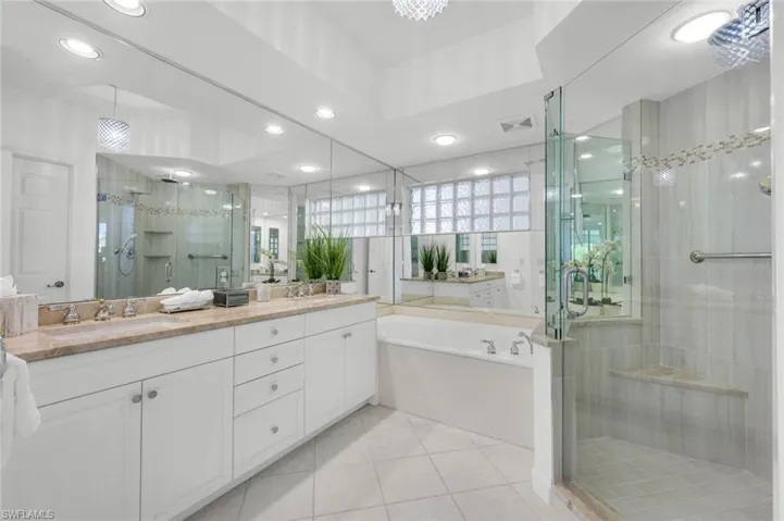 Full bathroom with a stall shower, a bath, light tile patterned flooring, double vanity, and recessed lighting