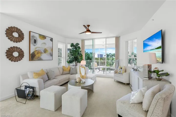 Carpeted living area featuring a ceiling fan and floor to ceiling windows