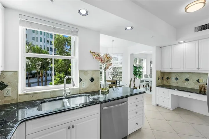 Kitchen featuring dark stone counters, backsplash, recessed lighting, dishwasher, and white cabinetry