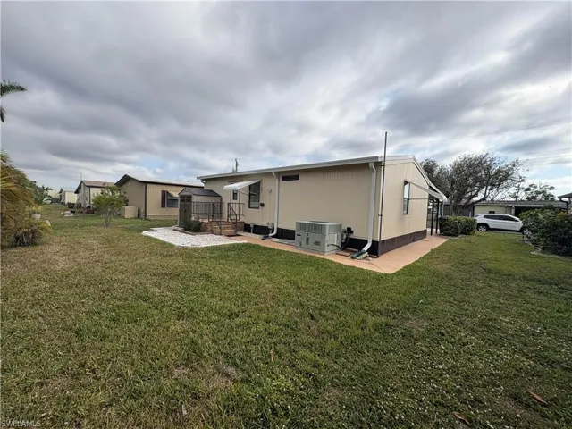 Back of property featuring central AC, a patio area, and a lawn