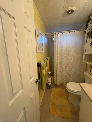 Bathroom featuring vanity, toilet, tile patterned flooring, and a textured ceiling